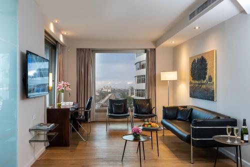 a living room with a couch and a large window at Leonardo City Tower Hotel Tel Aviv in Tel Aviv
