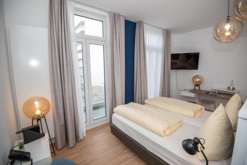 a bedroom with a bed and a large window at Design Hotel Sophie´s in Norderney