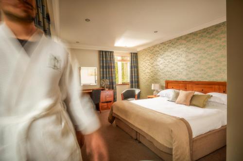 a man in a hotel room with a bed at Mallory Court Country House Hotel & Spa in Leamington Spa