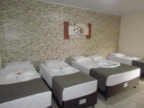 a room with four beds against a brick wall at Pousada Quinta Das Aroeiras in Olímpia