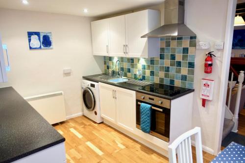een keuken met een fornuis oven naast een wasmachine bij Blue Cat Cottage in Penzance