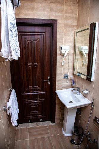 a bathroom with a wooden door and a sink at Mildom Hotel Baku in Baku
