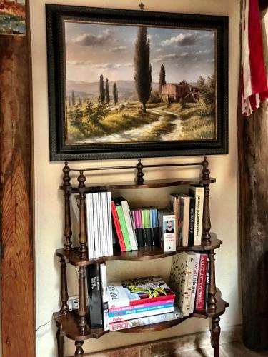 a book shelf filled with books under a painting at Borgo San Gusmè in San Gusmè