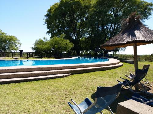 eine Gruppe von Stühlen und einem Sonnenschirm neben einem Pool in der Unterkunft Apart club San Pedro in San Pedro