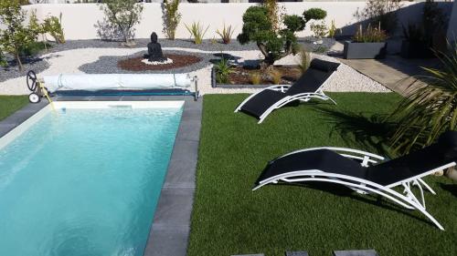 a backyard with a pool and chairs and a fountain at jardin zen in La Londe-les-Maures