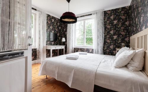 a bedroom with a large white bed with floral wallpaper at Strandvillan Ljugarn in Ljugarn