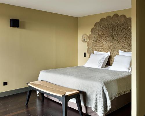 a bedroom with a large bed with a bench next to it at New Hotel Le Quai - Vieux Port in Marseille