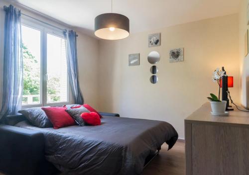 une chambre avec un lit avec des oreillers rouges et une fenêtre dans l'établissement SWEETHOME DIJON - Gare, à Dijon