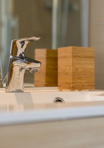 un lavabo de salle de bain avec un robinet et un miroir dans l'établissement SWEETHOME DIJON - Gare, à Dijon