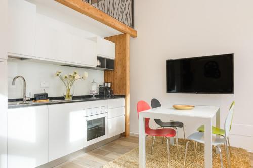 een keuken met een witte tafel en stoelen en een tv bij Vinci16 in Bolzano