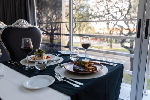 a table with two plates of food and glasses of wine at Ker San Telmo Hotel in Buenos Aires
