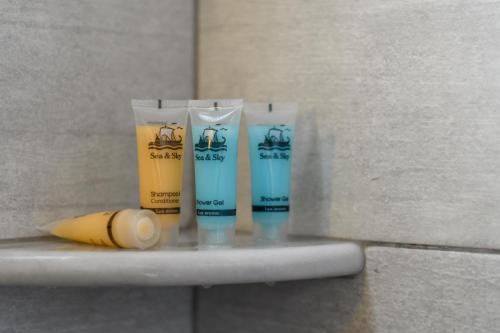 a group of three bottles of toothpaste on a shelf at Moonlight Apartments & Suites in Fira