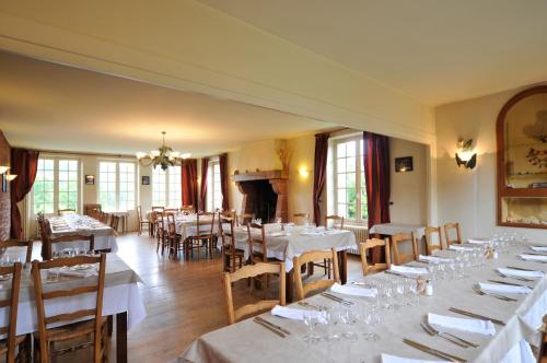 une salle à manger avec des tables et des chaises blanches et un piano dans l'établissement Le Relais St jacques, à Collonges