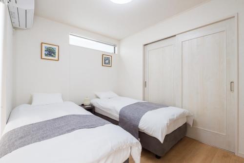 two beds in a room with white walls at Riverside Yofuke AFP Villa in Nago