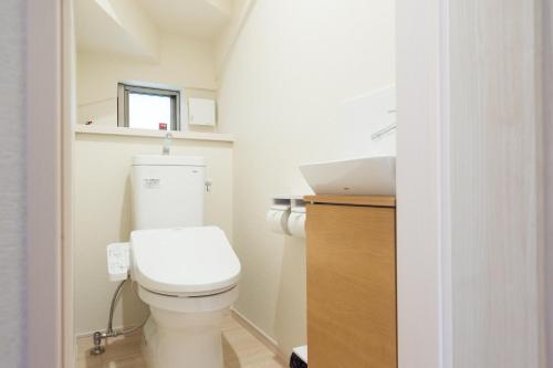 a bathroom with a white toilet and a sink at Riverside Yofuke AFP Villa in Nago