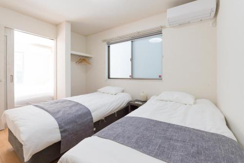 two beds in a room with two windows at Riverside Yofuke AFP Villa in Nago
