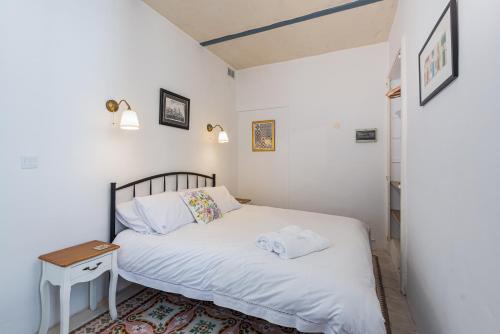 a small bedroom with a white bed and a table at Harbour Heights in Valletta