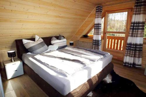 a large bed in a wooden room with a window at Chalet Fuchsberg in Mauth