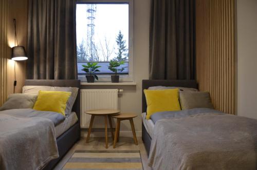 a room with two beds and a table and a window at "11" SŁOŃCE WODA LAS - Apartament No11 Garaż w cenie in Kielce