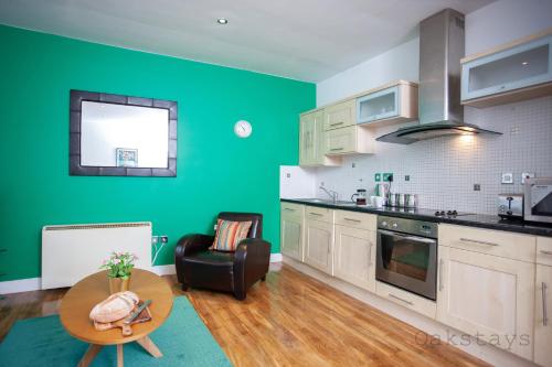 a kitchen with green walls and a table and a chair at Oakstays City Centre Gem in Newcastle upon Tyne