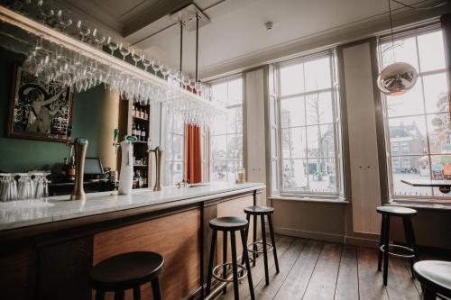 een bar met krukken in een kamer met ramen bij Brass in Utrecht