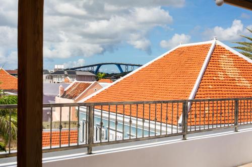 a balcony with an orange roof with a bridge in the background at BOHO Bohemian Boutique Hotel in Willemstad