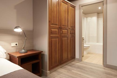 1 dormitorio con armario de madera, 1 cama y baño en Val de Ruda Luxe 9 by FeelFree Rentals, en Baqueira Beret