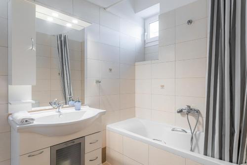 y baño blanco con lavabo y bañera. en Villa Porto- Naftilos Residences, en Pythagoreio