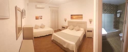 a hotel room with two beds and a bathroom at Hotel Almadrabeta in Zahara de los Atunes