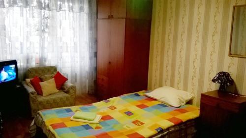 a bedroom with a colorful bed and a chair at Апартаменты в центре (Красная площадь) in Chernihiv