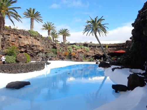 una piscina con agua azul y palmeras en Apartamentos Orzola, en Orzola