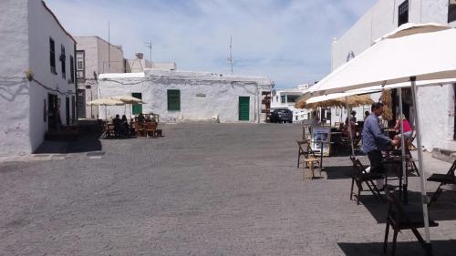 un grupo de personas sentadas en sillas en una calle en Home from Home 2, en Teguise