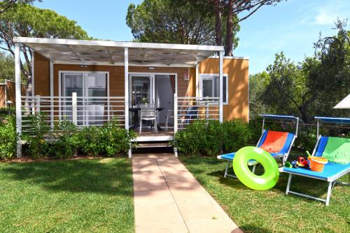 a tiny house with two chairs and a gazebo at Camping Village Baia Azzurra in Castiglione della Pescaia