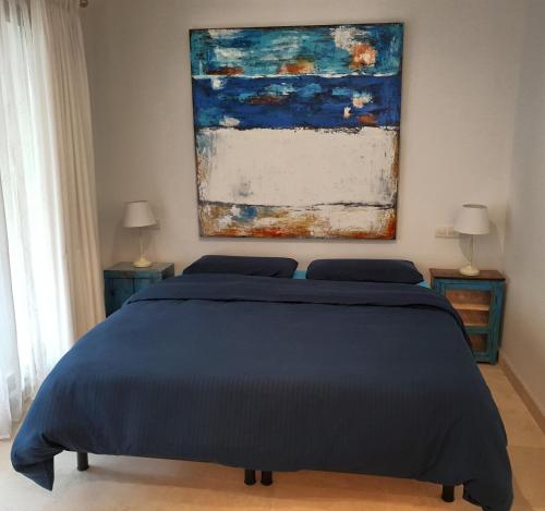 a bedroom with a blue bed and a painting on the wall at Garden Apartment in Finca Cortesin, Altos de Cortesin in Casares