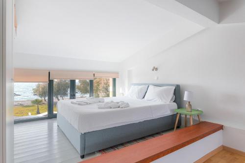 a white bedroom with a large bed and a window at Naftilos Residences I in Potokáki