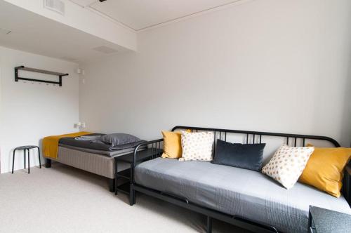 a room with two beds and a couch at Aikatalo Hostel Helsinki in Helsinki