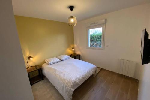 ein Schlafzimmer mit einem weißen Bett und einem Fenster in der Unterkunft Maison 50M de la mer in Lion-sur-Mer