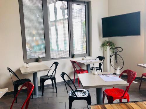 a restaurant with tables and red chairs and windows at All Suites Appart Hôtel - Bordeaux Centre Gare in Bordeaux