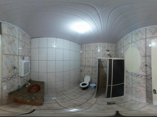 uma casa de banho com um chuveiro e um WC. em Pousada Parque Praia em Penha