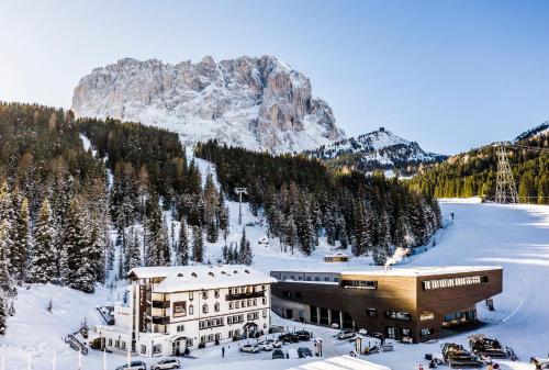 a building in the snow with a mountain in the background at Hotel Sella***s in Selva di Val Gardena