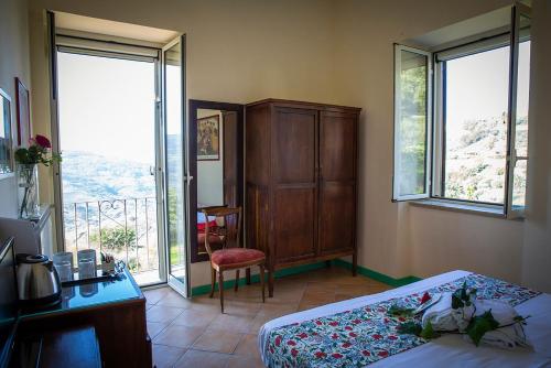 a bedroom with a bed and a desk and windows at B&B La Residenza Torchiara in Torchiara