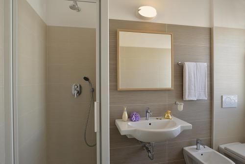 a bathroom with a sink and a mirror and a shower at Hotel Tiberius in Rimini