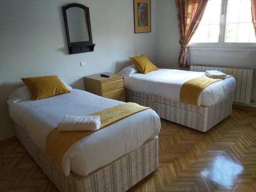 Cette chambre comprend 2 lits et un miroir. dans l'établissement Chalet Avila Rooms, à Madrid