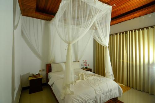 a bedroom with a white bed with white curtains at Bintang House in Kintamani