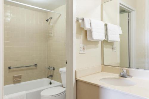 a bathroom with a sink and a toilet and a mirror at Traveler's Place Inn & Suites in Scottsboro
