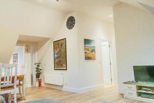 a living room with a clock on the wall at Garrykennedy Harbour View Apartment in Nenagh