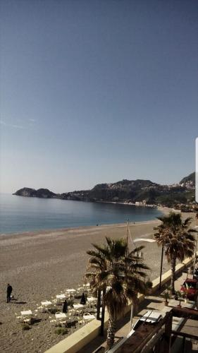 a beach with chairs and palm trees and a person on the beach at La Casita Il Poggio Del Sole in Letojanni
