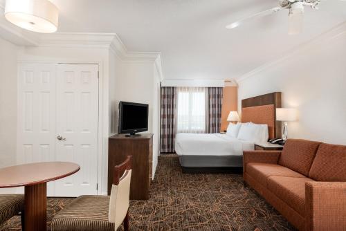 a hotel room with a bed and a couch and a television at Holiday Inn Fort Lauderdale Airport, an IHG Hotel in Hollywood