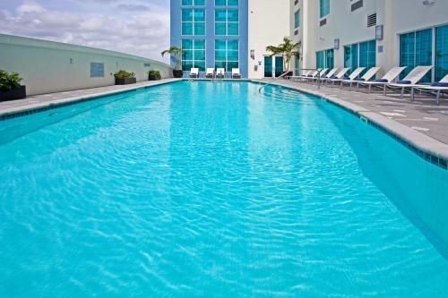 a large blue swimming pool with chairs and a building at Crowne Plaza Hotel & Resorts Fort Lauderdale Airport/ Cruise by IHG in Fort Lauderdale