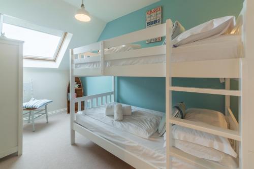 two bunk beds in a room with a window at Curlew's Cwtch in Wadebridge